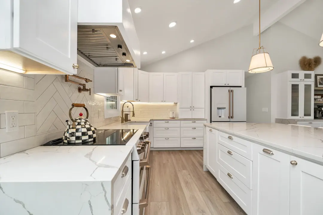Bright white kitchen with a marble backsplash and wood floors