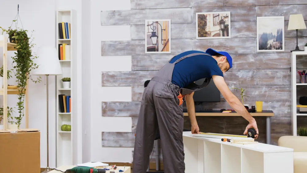 Carpenter measuring and installing a built-in shelving unit