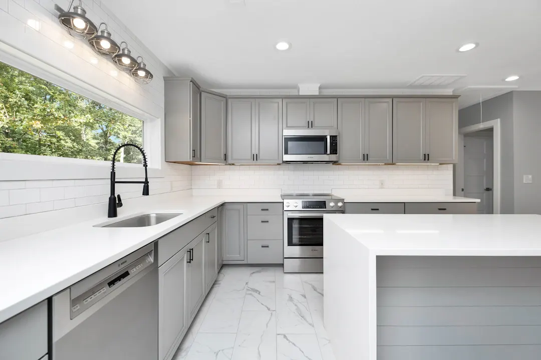 Gray shaker kitchen with a black faucet under the window