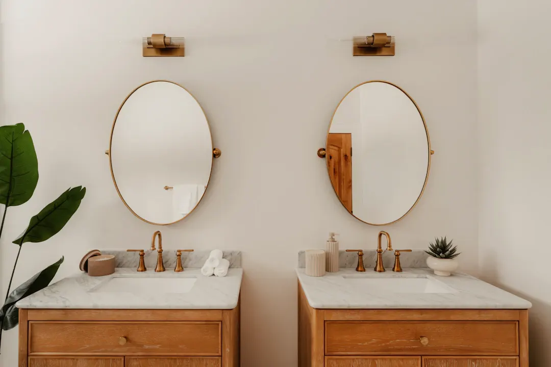 Two separate wood vanities with oval brass mirrors