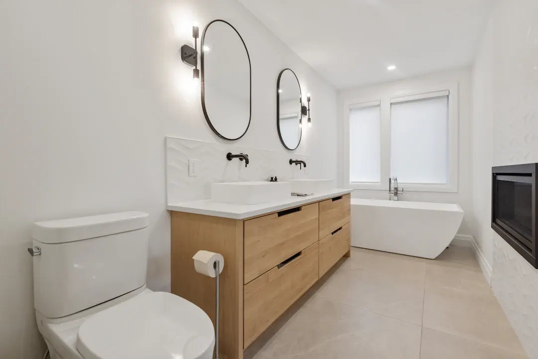 Modern bathroom with an oak floating vanity, round mirror and freestanding tub