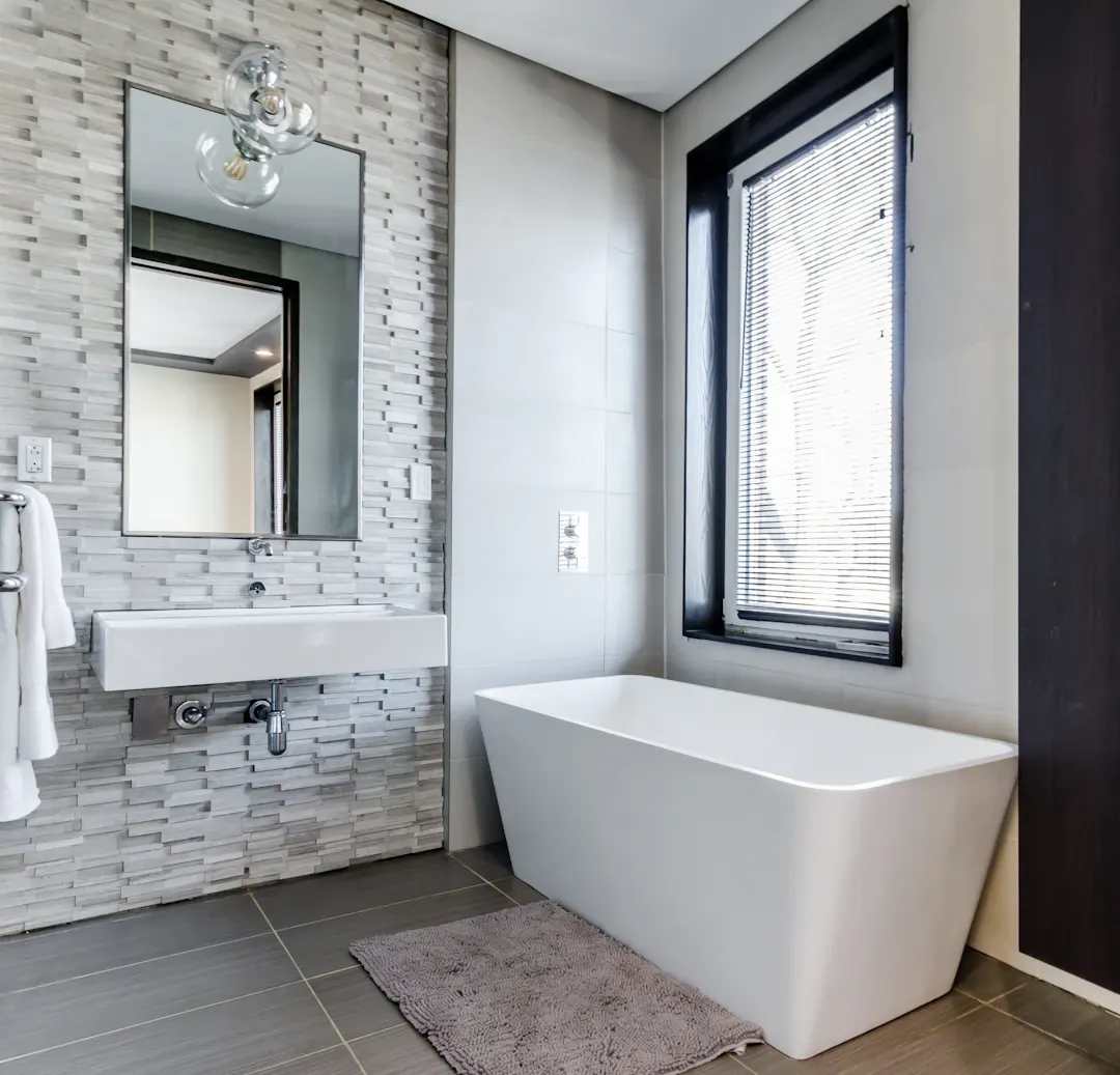 Small bathroom with a wall-hung sink, stacked-stone tile and a freestanding tub